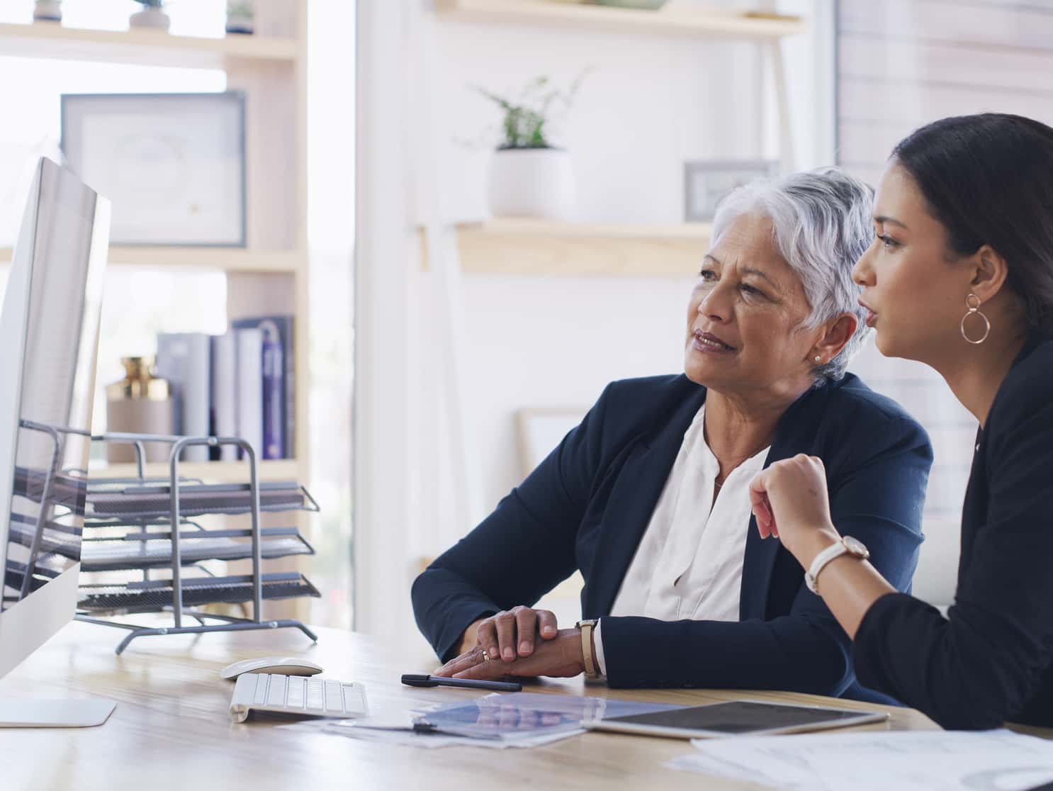 Insurance professional explaining Medicare plan details to a senior client at a desk